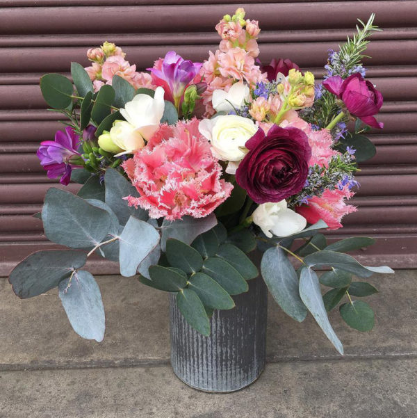 A metal vase filled with flowers arranged by Bloom Sacramento.