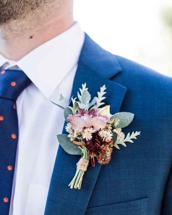 Man wearing blue suit wears boutonniere made by Bloom Sacramento