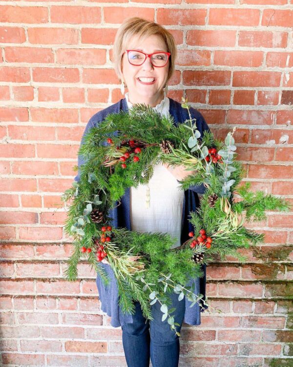Woman hold wreaths made at workshop hosted by Bloom Sacramento