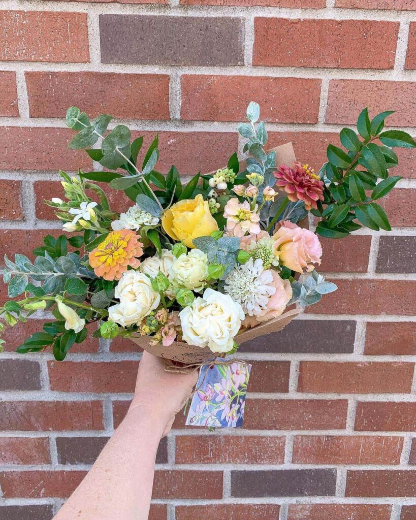 Arranged bouquet from Bloom Sacramento held in front of a brick background