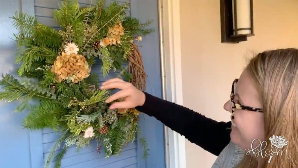 Amanda Kitaura of Bloom hangs up a finished wreath during the filming of an instructional video