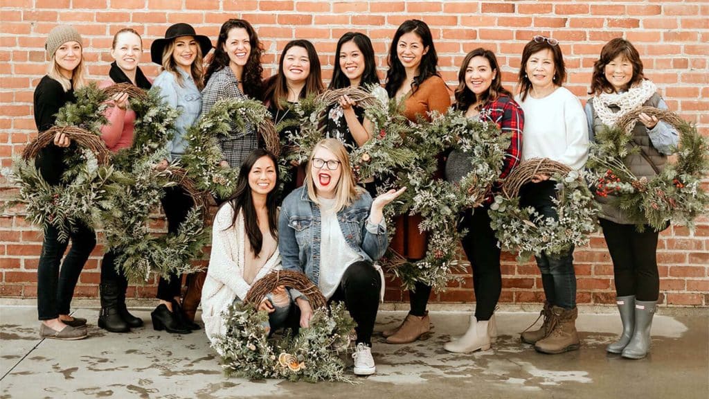 People hold wreaths that they made at Bloom Sacramento workshop