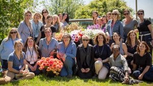 Group of women pose for photo with flowers next to small pickup truck