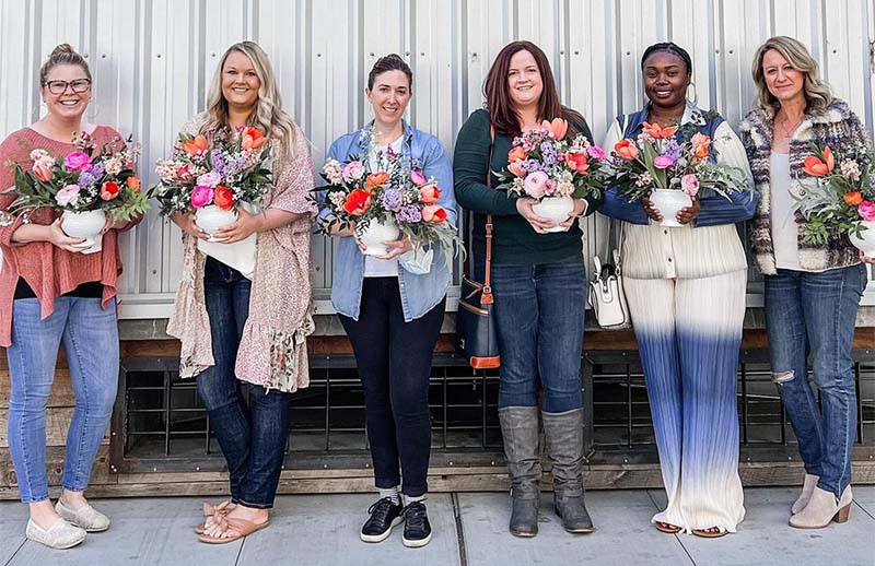 Attendees at a Bloom workshop hold flower arrangements they created