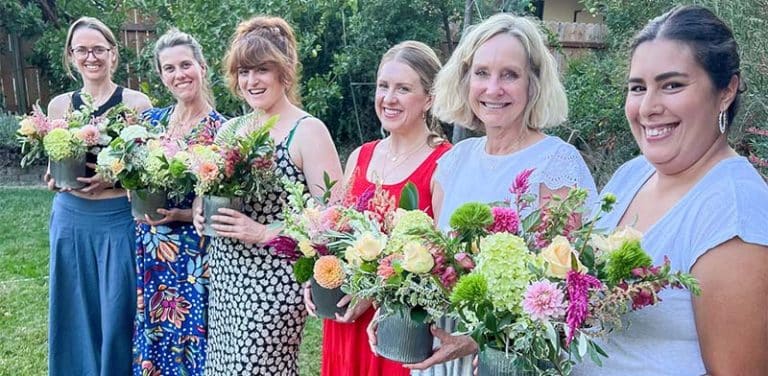 Attendees at a Bloom workshop hold flower arrangements they created