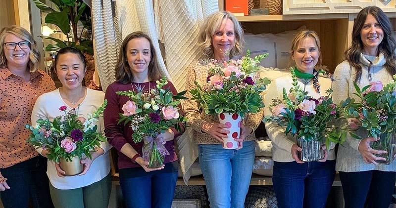 Attendees at a Bloom workshop hold flower arrangements they created