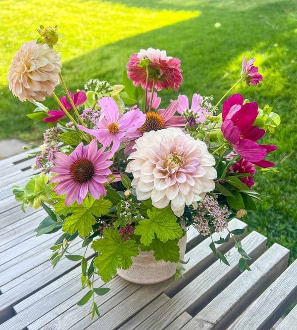 A flower arrangement in a vase sits on a wooden table