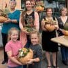 Group of people hold pumpkins decorated with dried flowers and other additions.