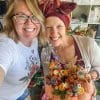 Two people pose for a photo in front of a pumpkin decorated with dried flowers and other additions, created by Bloom Sacramento