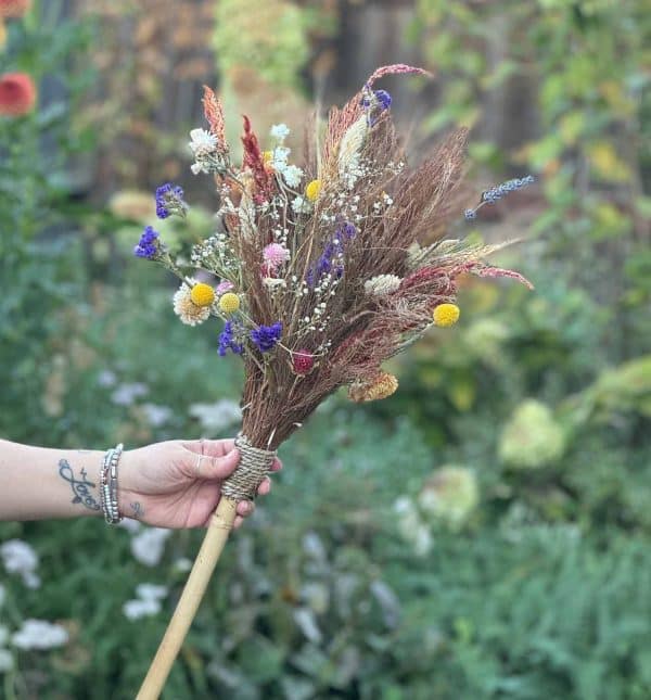 Person holds witch's broom created at workshop hosted by Bloom Sacramento