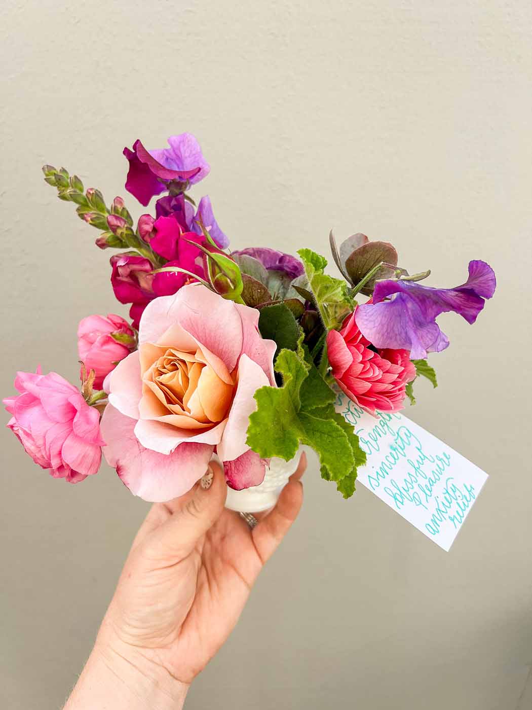 Hand holding Bloom Sacramento flower arrangement with card showing meaning of flowers included